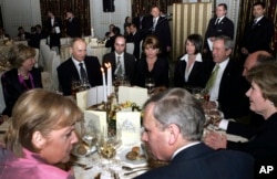 Анґела Меркель із тодішнім генсекретарем НАТО Яапом де Гооп Схеффером на передньому плані, Володимир Путін – на задньому плані другий зліва, Джордж Буш – третій справа, відвідують рецепцію у Бухаресті під час саміту НАТО у 2008 році