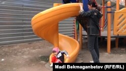 Ақсай-4 ықшам ауданының тұрғындары дуал сыртына ысырылған сырғанақта балаларын ойнатып жүр. Алматы, 7 сәуір 2012 жыл.