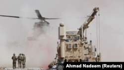 U.S. troops assess the damage to an armored vehicle of NATO-led military coalition after a suicide attack in the southern province of Kandahar in August 2017.