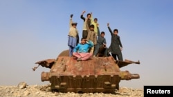 Afghan children play on the remains of a Soviet-era tank on the outskirts of Jalalabad in February.