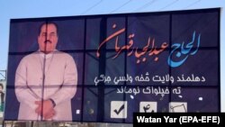 Afghan people walk past an electoral billboard of Abdul Jabar Qahraman, a prominent Afghan politician and candidate of upcoming Parliamentary elections, after he was killed in a suicide bomb attack, in Helmand on October 17.