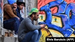 Migrants sit in front of an abandoned building in the northwestern Bosnian town of Velika Kladusa in May.