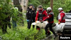 Emergency workers carry the body of a resident who died when a Russian drone hit an apartment building in Kyiv on May 7.
