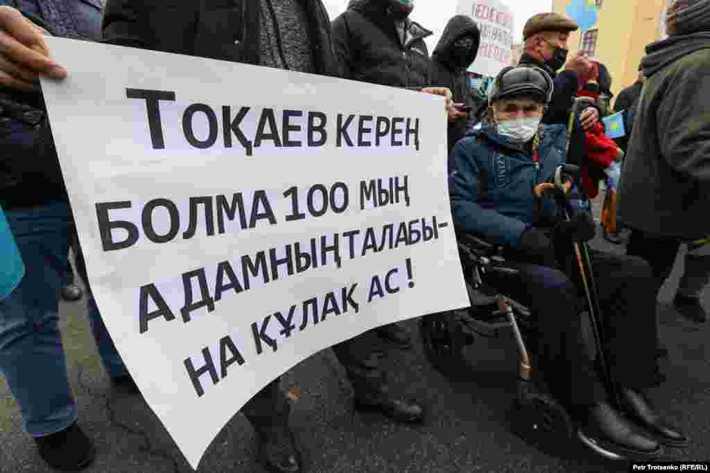 Мүгедек арбасына отырған ер кісі Алматыдағы митингіде. Плакатта "Тоқаев керең болма, 100 мың адамның талабына құлақ ас!" делінген. Тамыз айында Демократиялық партияны құру жөніндегі Жанболат Мамай бастаған бастамашыл топ Қазақстан президенті Қасым-Жомарт Тоқаевтың әкімшілігіне несие амнистиясын жариялау туралы 100 мыңға тарта өтініш тапсырылғанын айтты.