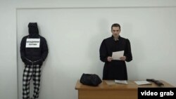 Karim Yamadayev (right), dressed as a judge, reads death sentences for the men portrayed in his video.