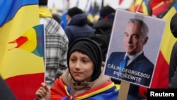 ანტისამთავრობო მიტინგის მონაწილე კალინ ჯორჯესკუს პორტრეტით 