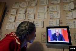 Женщина смотрит выпуск телевизионных новостей, где показывают речь президента России Владимира Путина на заседании правительства. Санкт-Петербург, 30 сентября 2015 года.