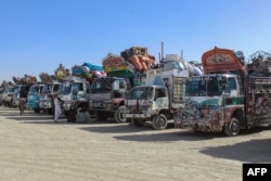 Afghan refugees wait beside trucks loaded with their belongings before departing to Afghanistan at a holding center near the border in Chaman, Pakistan, on April 27.