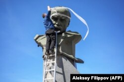 Активіст робить символічні пов’язки на осколкових отворах на голові пам’ятника Тарасу Шевченку, пошкодженому обстрілами російських військових під час масштабного вторгнення Росії до України. Бородянка, Київська область, 7 квітня 2022 року