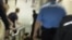 Скриншот появившегося в Интернете видео, в котором милиционеры тащат вниз по лестнице инвалида.  