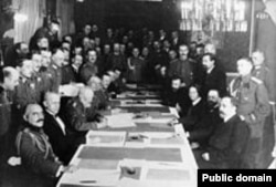 Semnarea Tratatului de la Brest Litovsk în martie 1918 de bolșevicii ruși (dreapta) și germani & austrieci (stânga). Șeful comunist, V. I. Lenin, radical rus, fusese plătit de Berlin să creeze dificultăți țarului. A depășit așteptările cu o sută de ani și milioane de morți.