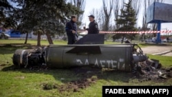 Українські силовики біля фрагмента ракети «Точка-У» з написом російською мовою «За детей» після ракетного удару російськими військами по залізничному вокзалі в Краматорську, 8 квітня 2022 року