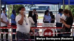 Люди стоят в очереди у центра тестирования на COVID-19 в Алматы. 