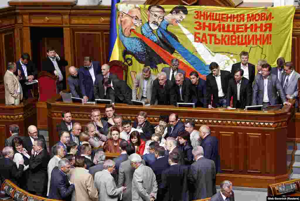 Опозиційні депутати блокують трибуну парламенту.&nbsp;На банері зображені (зліва направо): прем'єр Микола Азаров, міністр освіти Дмитро Табачник і президент Віктор Янукович. Київ, 25 травня 2012 року&nbsp;