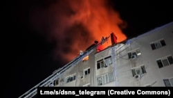 Pompierii lucrează să stingă un incendiu la un bloc de locuințe lovit de atacurile rusești cu drone iraniene - Nikolaev, Ucraina, în zorii zilei de 22 ianuarie.