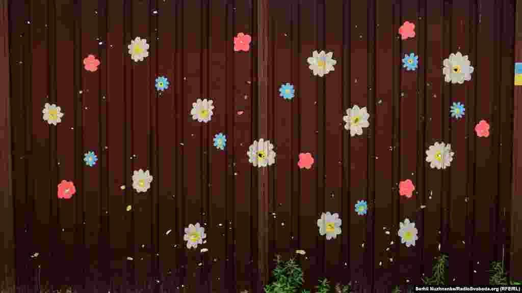 На воротах житлового будинку намальовані квіти навколо слідів від уламків снарядів