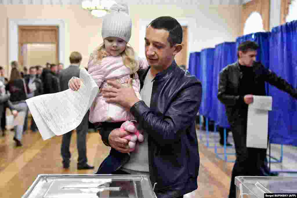 A little girl casts a man's ballot in Kyiv. (AFP/Sergei Supinsky)