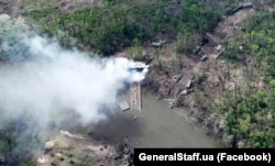 Згоріла техніка армії Росії і знищена понтонна переправа російських військових після ударів ЗСУ на березі річки Сіверський Донець на Донбасі. Травень 2022 року