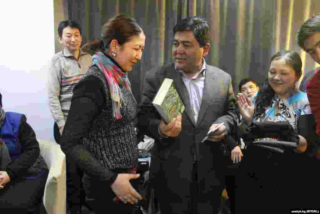 "Азаттыктын" веб-редактору Шайырбек Мукарамов Бегимай Асеевага сыйлык тапшырууда.