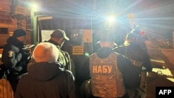 Službenici Nacionalnog biroa za borbu protiv korupcije Ukrajine prolaze kroz kontrolni punkt u vladinom okrugu u Kijevu u toku pretresa kancelariju Andrija Jermaka rano 28. novembra 2025.