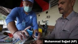 A volunteer helps a passenger arriving at a railway station to wash hands as a measure to help prevent the spread of the coronavirus in the northwestern city of Peshawar on March 17.