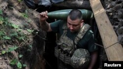 Військовослужбовець 30-ї ОМБр ЗСУ імені князя Костянтина Острозького несе снаряд для самохідної гаубиці 2С1 «Гвоздика» на передовій у Донецькій області, 13 серпня 2025 року