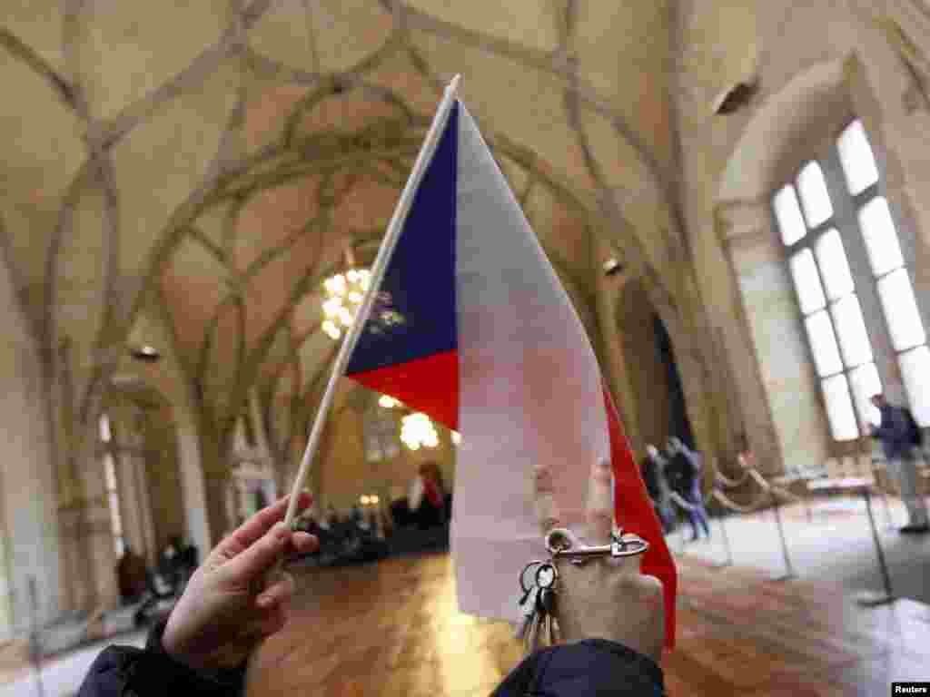 A man waves a Czech flag and a set of keys in homage to Vaclav Havel inside Prague Castle. The jingling of keys, symbolizing the "unlocking of doors," was a major component of mass demonstrations led by Havel on Wenceslas Square in 1989.