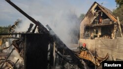 یو اوکراینی کارکوونکی له لفیف ښاره بهر پر ودانۍ د روسیې تر برید وروسته د اور وژلو هڅه کوي - د اګست ۲۱مې انځور.