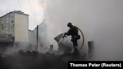 Орус армиясынын соккусунун кесепетинен тутанып жаткан өрттү өчүрүп жаткан куткаруучу.