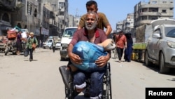 Un palestinian în cărucior cu rotile, purtându-și protezele, pleacă din calea noii ofensive israeliene, în orașul Gaza, pe 26 august. 