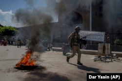An Indian security officer walks past a burning tire amid unrest by Kashmiri protesters in Srinagar late last month.