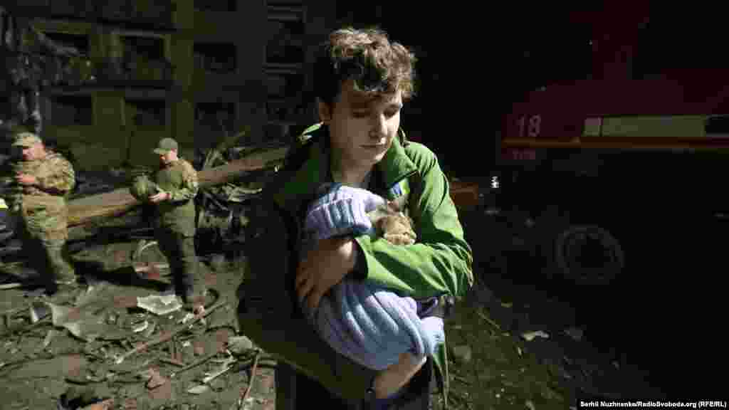24 aprilie 2025, Kiev, Ucraina – Un băiat salvează o pisică din ruinele unui bloc de apartamente din cartierul Sviatoshinski, lovit de de o rachetă rusească. 