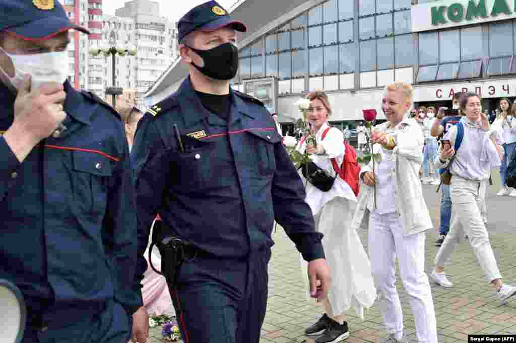 Anti-government protesters offer flowers to two police officers in Minsk on August 12.