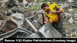 په کوهستان کې د رېسکیو ۱۱۲۲ یو کارکوونکی کندې ته له پرېوتي ګاډي څخه د ژوبلو کسانو ایستلو هڅه کوي - د مې لومړۍ انځور.