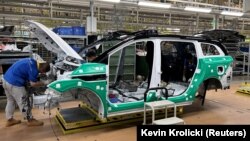 Angajați care lucrează la un vehicul electric (EV) de pe o linie de producție a unei fabrici care aparține Jiangling Group Electric Vehicle in Nanchang, provicia Jiangxi, China.