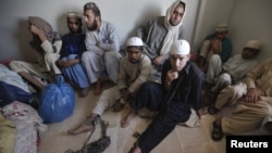 Students wear chains around their ankles while sitting with their belongings at a police station after being rescued during a late-night raid on December 12-13 at the Zakariya madrasah on the outskirts of Karachi.