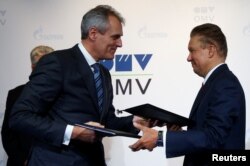 Directorul executiv al grupului austriac de petrol și gaze OMV Rainer Seele (s) și directorul executiv al Gazprom, Aleksei Miller (d), schimbă contracte în timpul unei conferințe de presă la Viena, 14 decembrie 2016.