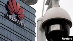 O cameră de supraveghere în fața logo-ului Huawei, la fabrica din Dongguan, provincia chineză Guangdong.