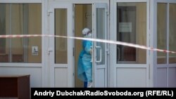 Медик Калинівської лікарні у повному захисному костюмі зачиняє двері корпусу №1, який зараз знаходиться на повному карантині