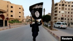 A member of Islamic State militants waves the group's flag in the Syrian city of Raqqa in June.