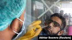A paramedic wearing protective gloves takes a nose-swab sample to be tested for the coronavirus in Karachi.