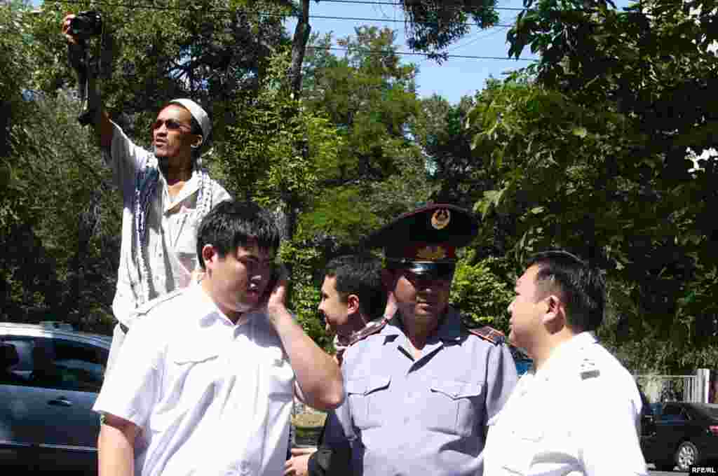 Сотрудники прокуратуры и полиции наблюдают за акцией журналистов в защиту свободы слова.  - Фотокорреспондент фотографирует участников митинга в защиту СМИ. За акцией наблюдают сотрудники прокуратуры и полиции. Алматы, 24 июня 2009 года. 