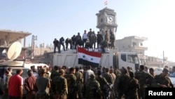 Government soldiers and civilians gather as they place the Syrian national flag on a truck in Qusayr on June 5.