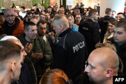 Польські поліцейські розмовляють з українцями, які зібралися перед закритим пунктом видачі паспортів України в торговому центрі у Варшаві, Польща, 24 квітня 2024 року.