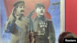 Посетитель выставки «Победа» смотрит на плакат с изображением Иосифа Сталина. Москва, 23 апреля 2010 года.