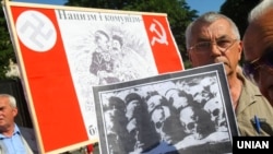 Учасник мітингу-реквієму тримає фото черепів та тлі плаката із зображенням Сталіна та Гітлера в день пам’яті жертв комуністичного і нацистського режимів. Львів, 22 червня 2011 року 