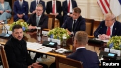 Președintele Ucrainei, Volodimir Zelenski, la masă cu președintele SUA, Donald Trump, președintele Franței, Emmanuel Macron, prim-ministrul britanic, Keir Starmer, și președintele Finlandei, Alexander Stubb (cu spatele), în discuții la Casa Albă, pe 18 august 2025.