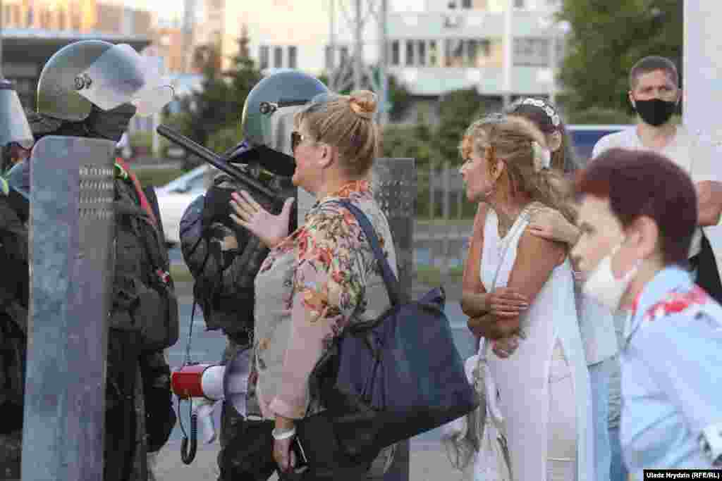 People talk to Belarusian law enforcement officers in Minsk on August 11.