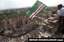 Чеченець із прапором Ічкерії на даху зруйнованого президентського палацу під час святкування четвертої річниці одностороннього проголошення незалежності, Грозний, 7 вересня 1995 року