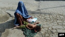 یک خانم گدا ظاهراً با کودکش در یکی از جاده های شهر کابل - عکس از آرشیف